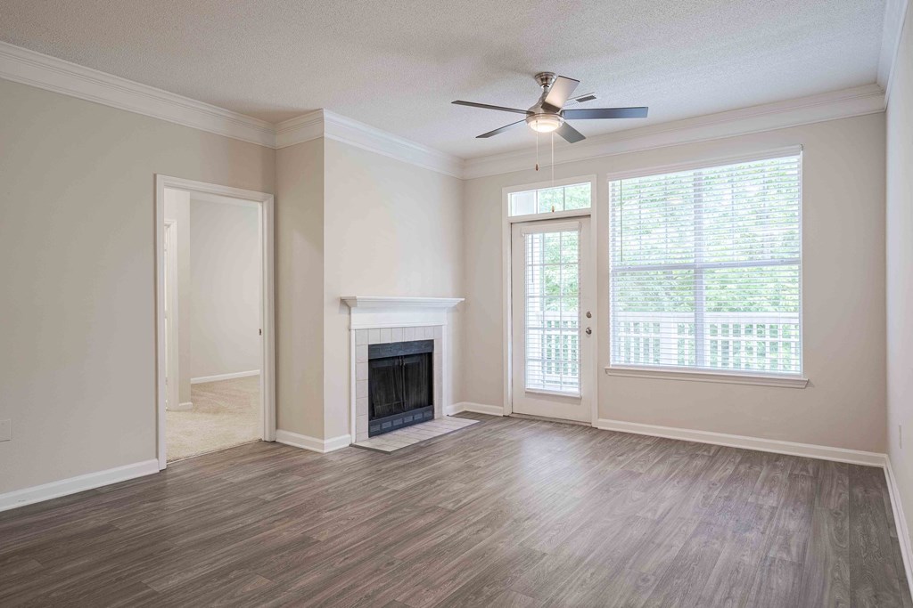 an empty living room with a fireplace and a ceiling fan