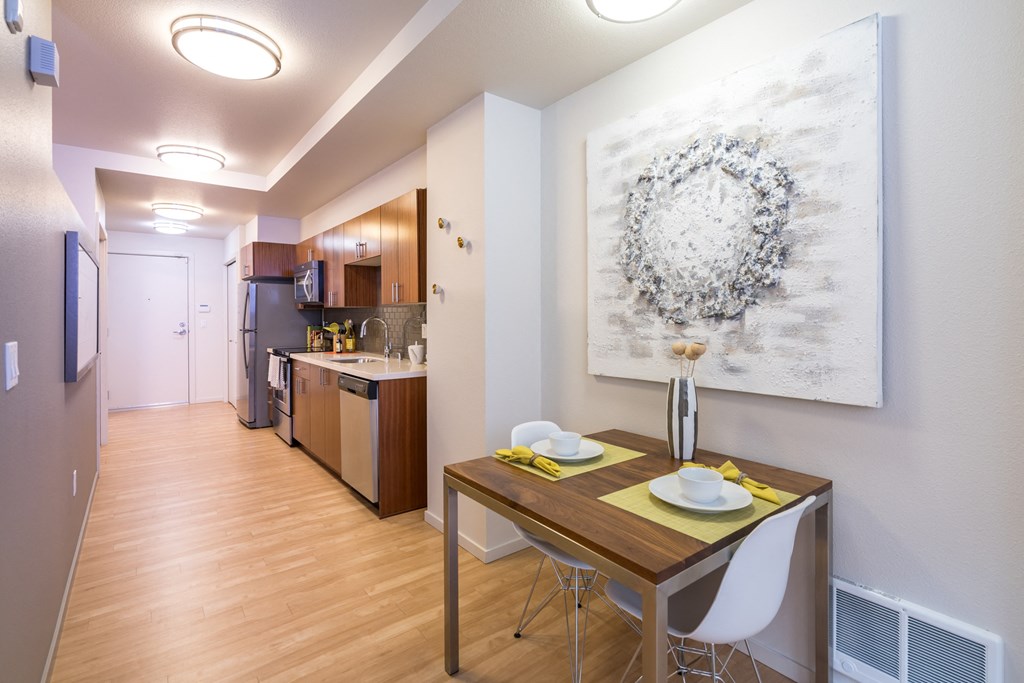 a dining room and kitchen with a table and chairs and a painting