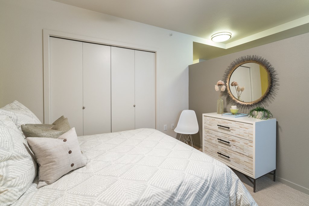 a bedroom with a bed and a dresser with a mirror