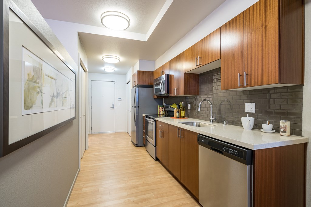 a kitchen with wooden cabinets and stainless steel appliances and a white counter top