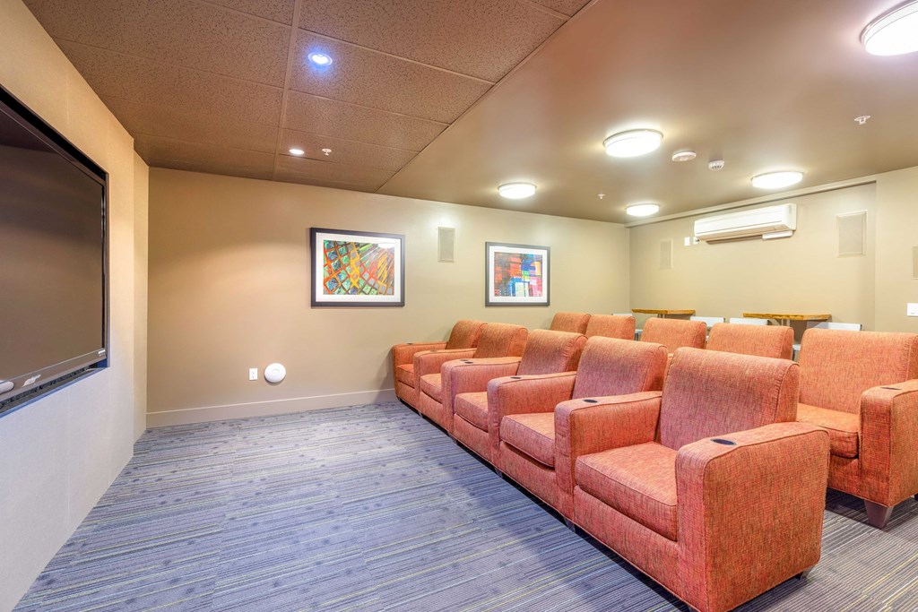 a spacious theater room with orange couches and a tv