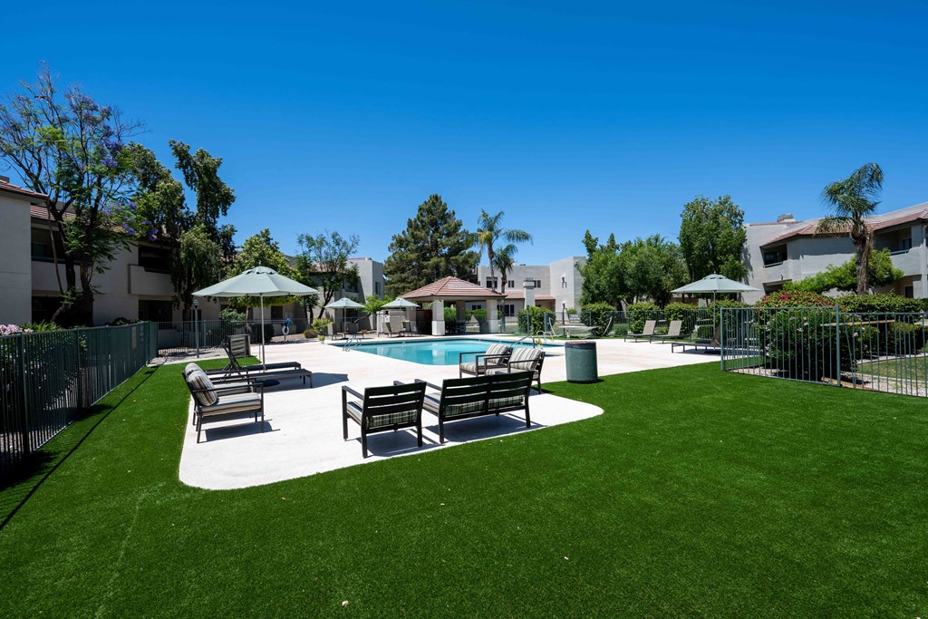 1-Bedroom Apartments in Ahwatukee, Phoenix, AZ - Village at Lakewood - Pool Area with Artifical Turf, Pool, Sundeck with Lounge Seats and Umbrellas.