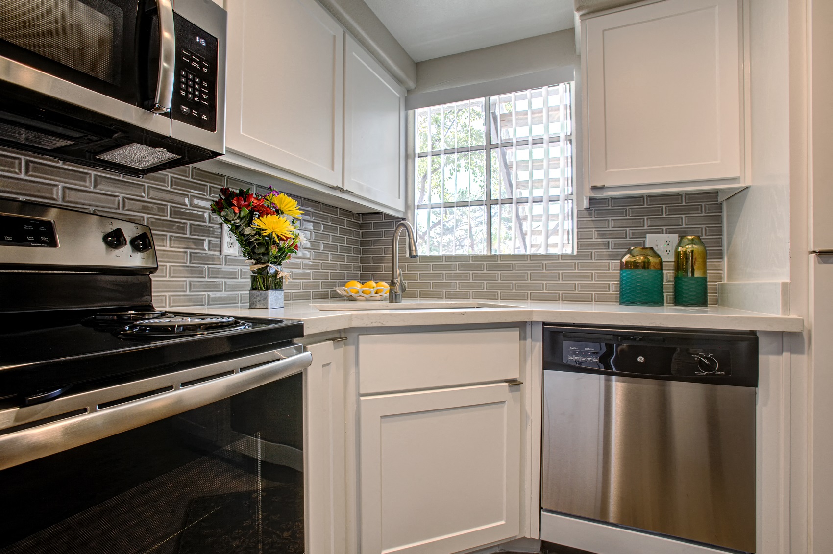 Luxury Apartments in Phoenix AZ - Village at Lakewood - Modern Kitchen with Tiled Backsplash, White Cabinetry, and Stainless-Steel Appliances