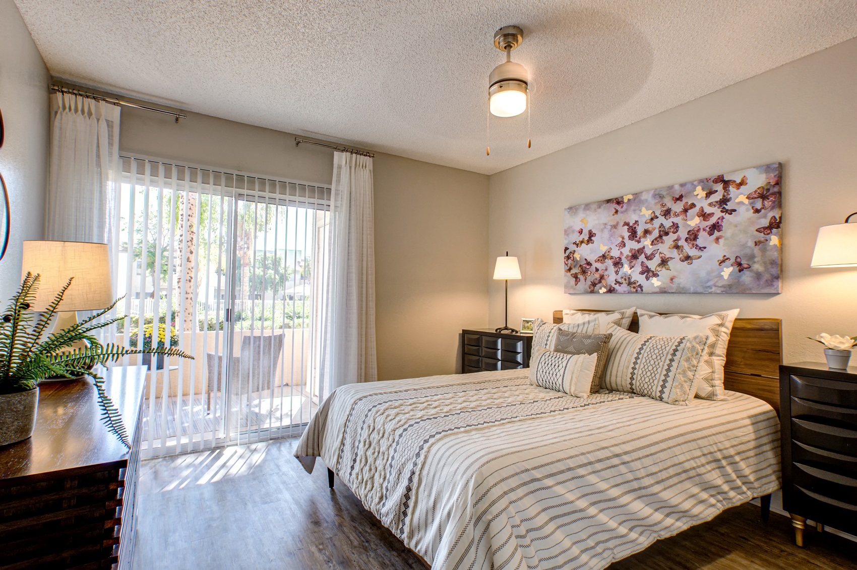 Pet-Friendly Apartments in Phoenix AZ - Village at Lakewood - Bedroom with Wood-Style Flooring and Access to Patio
