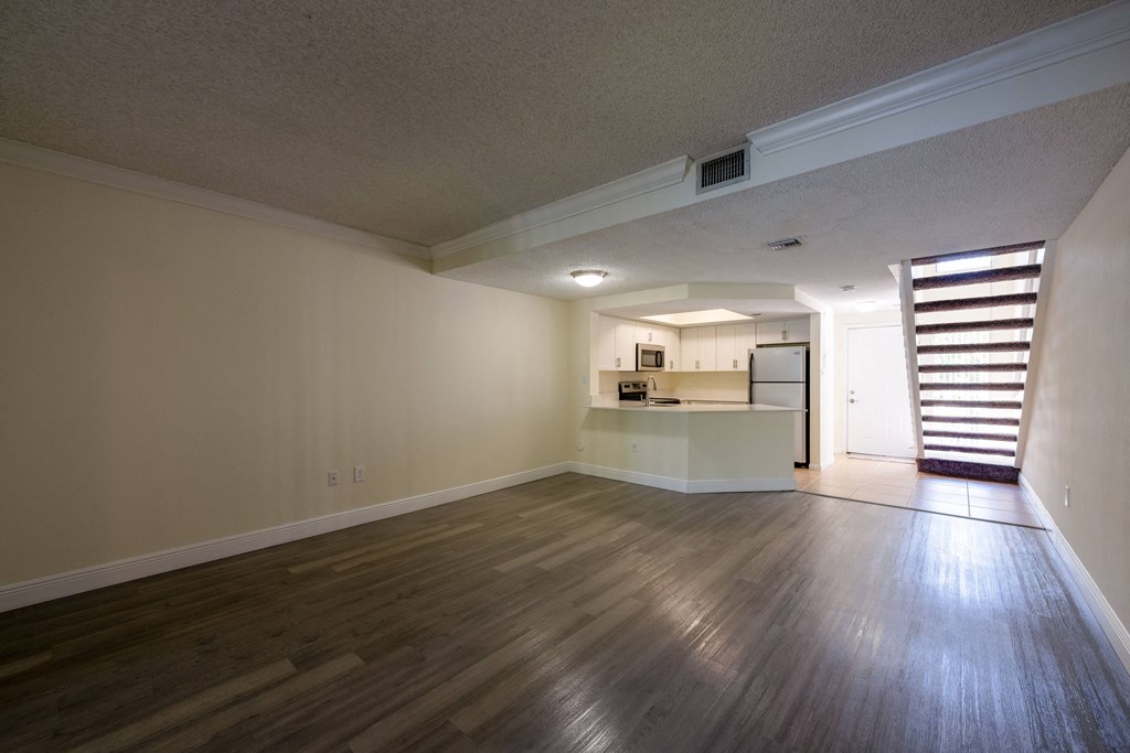 Pet-Friendly Apartments in Coconut Creek, FL – Waterview at Coconut Creek – empty living room with wood floors and a kitchen
