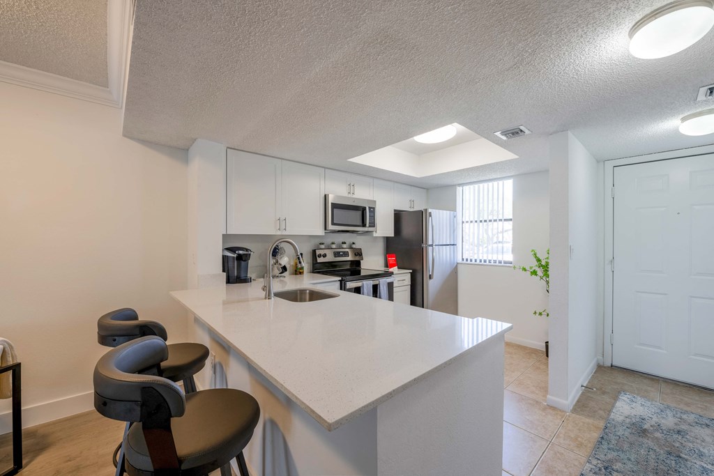 Pet-Friendly Apartments in Coconut Creek, FL – Waterview at Coconut Creek – kitchen with an island and stools in front of a kitchen counter top