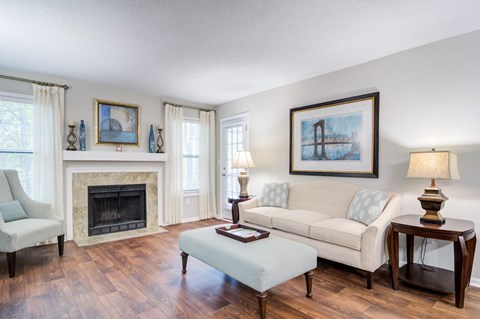 A living room with a fireplace, two couches, a chair, and a painting on the wall.
