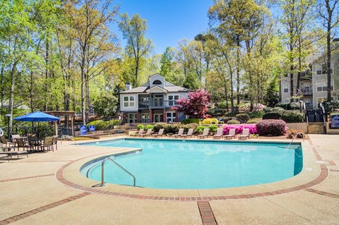 Apartments in Marietta Georgia for Rent – Wood Pointe Apartments - A large swimming pool surrounded by trees and a building in the background.