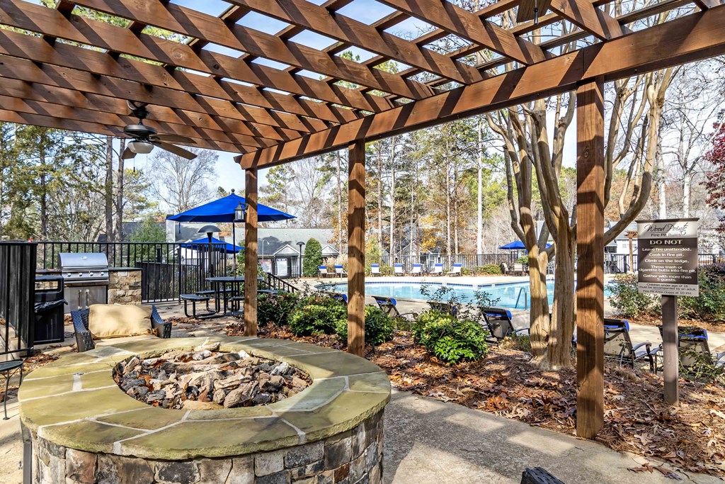 Wood Pointe Apartment Homes in Marietta Georgia photo of an outdoor patio with a fire pit and pergola with a pool in the background