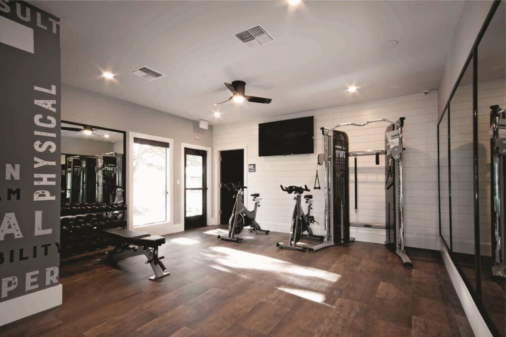 A gym with a variety of equipment including a treadmill, weights, and a television.