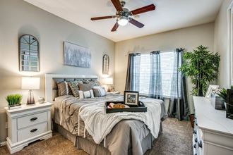 Apartment Houston, TX - Spacious Bedroom with Plush Carpet, a Large Window, and a Ceiling Fan