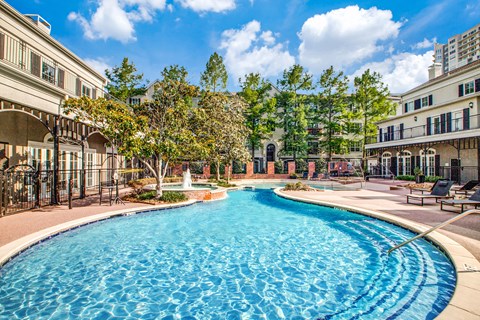 Washington Avenue Coalition, TX, Luxury Apartments Near Upper Kirby - Marcella Memorial Heights - A Swimming Pool Surrounded By Elegant Buildings, Lush Landscaping, And Sun Loungers.