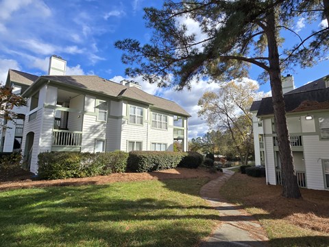 A white apartment building with a tree in front.