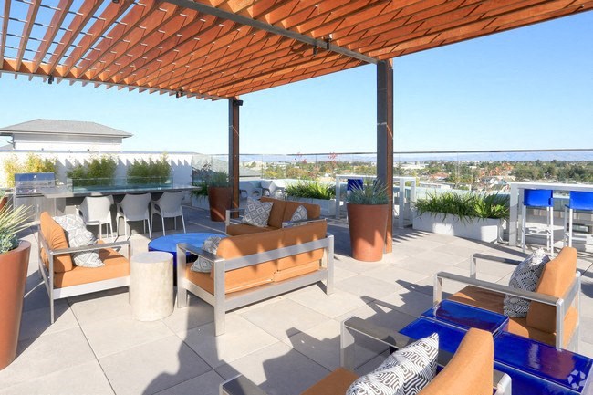 a roof top patio with furniture and a view of the ocean