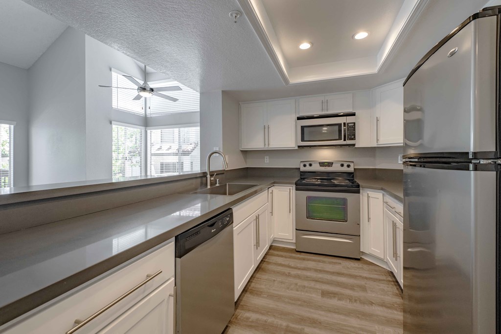 Apartments for Rent in San Clemente - Rancho Del Mar - Kitchen with Stainless Steel Appliances, Hardwood-Inspired Flooring, and White Cabinetry