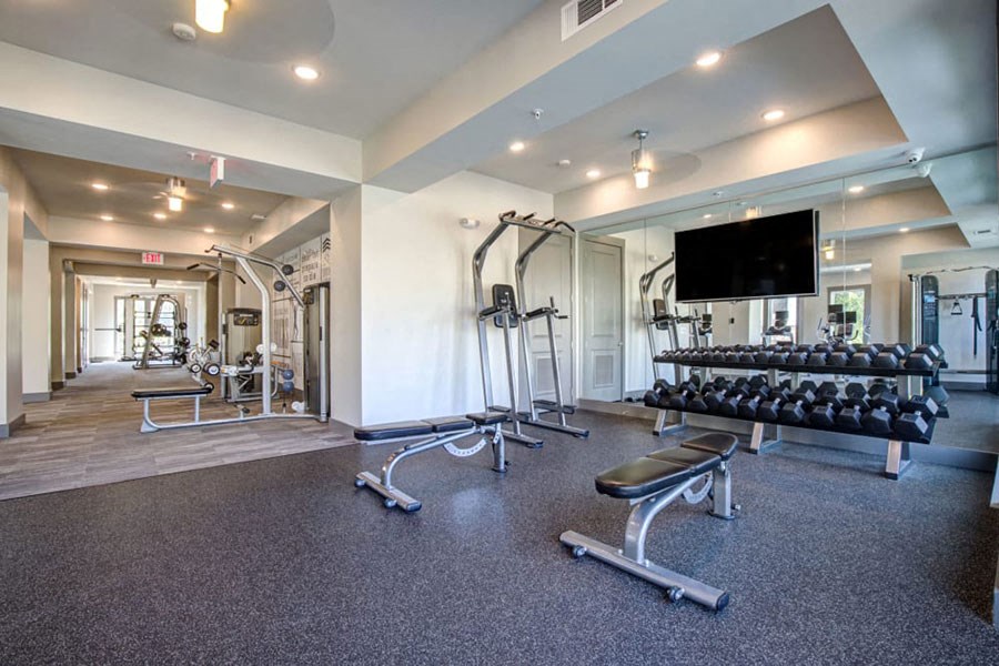 a gym with weights and a tv on the wall