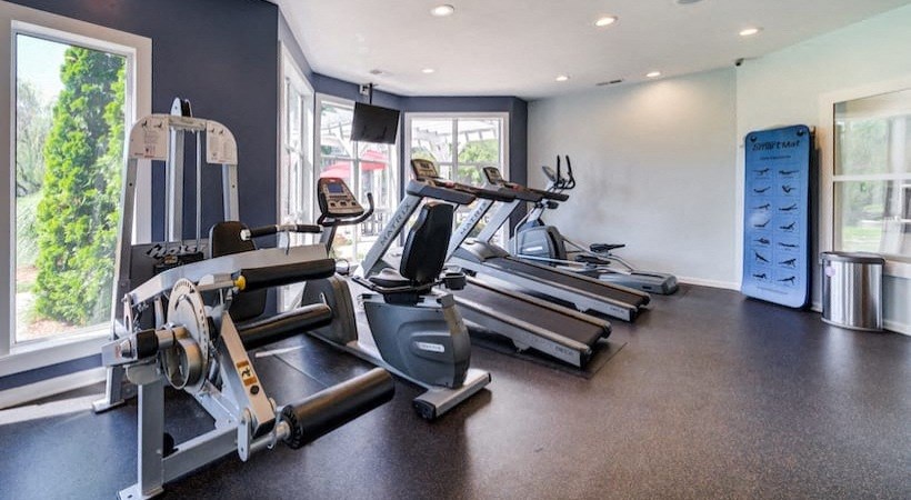 a gym with cardio equipment on the floor and a large window