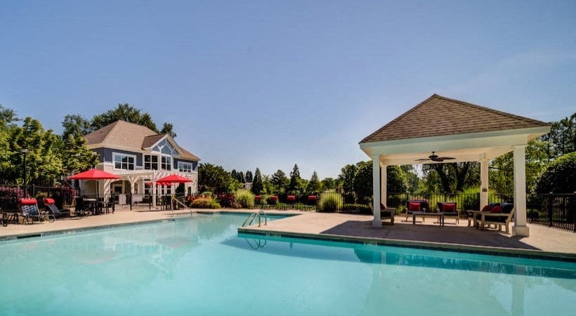 a swimming pool and pavilion with a house in the background