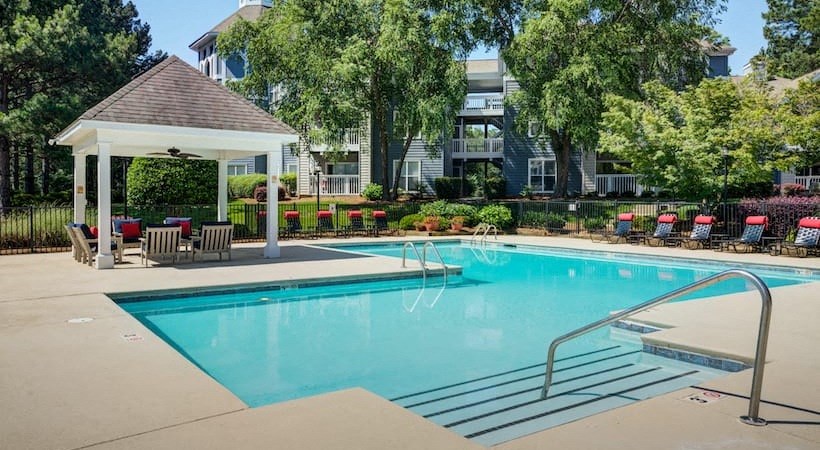 a pool with chairs and a gazebo next to a resort style pool