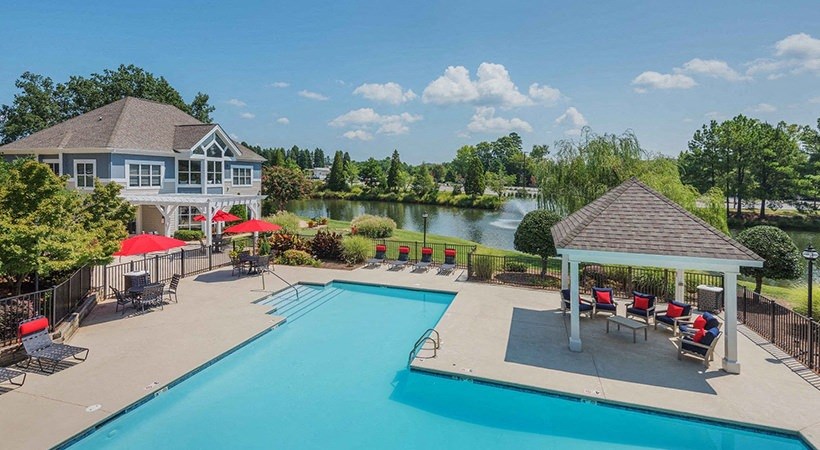 a swimming pool with patio furniture and a house overlooking a lake