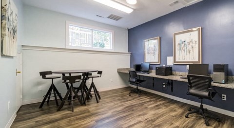 A business office with a table and chairs and two computers on a desk.