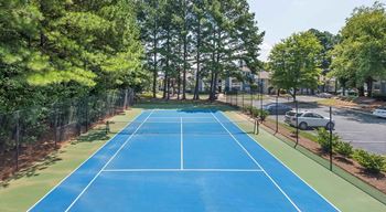 a blue and green tennis court with trees in the background