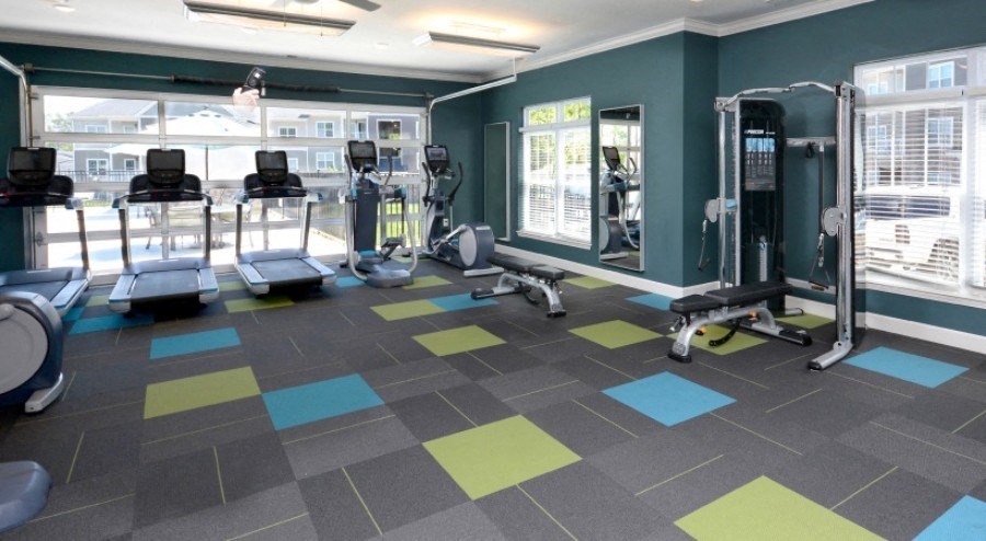 A gym with a variety of equipment including treadmills, weights, and exercise machines.