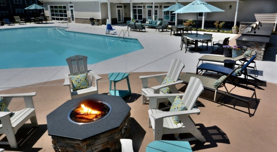 A fire pit sits in the middle of a patio with chairs around it.