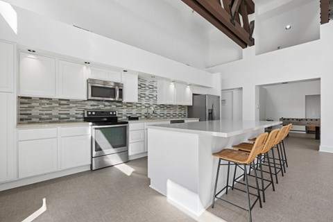 A modern kitchen with white cabinets and a stone backsplash.