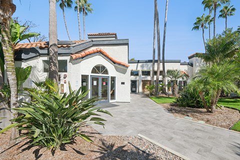 A building with a red tile roof and palm trees in front.