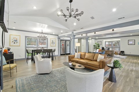 A living room with a brown couch and a chandelier.