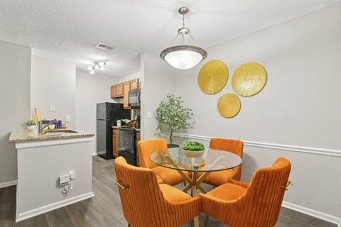 A dining room with a glass table and orange chairs.