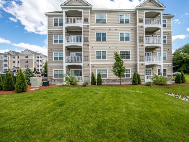 an apartment building with a large green lawn
