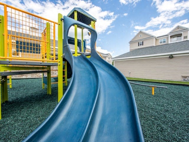 a slide in a playground with houses in the background