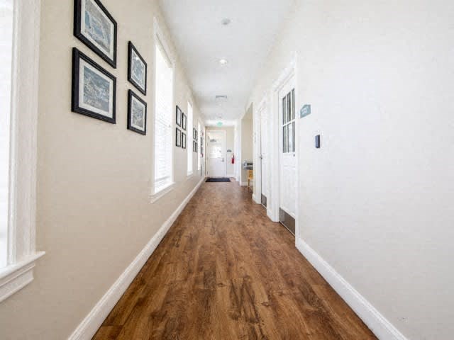a hallway with white walls and a wooden floor