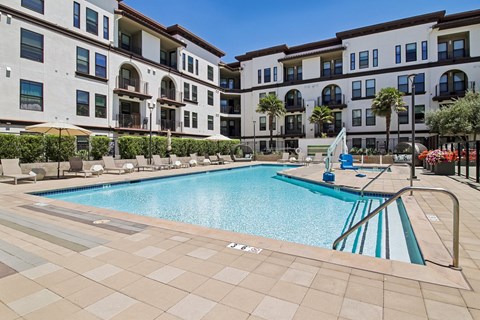 A large swimming pool in front of a building with a blue sky in the background.