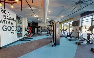 a gym with weights and cardio equipment and a wall with a quote