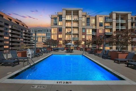 A large swimming pool in front of apartment buildings with a "No Diving" sign.