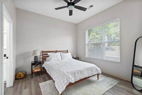 A bedroom with a bed, nightstand, and window.