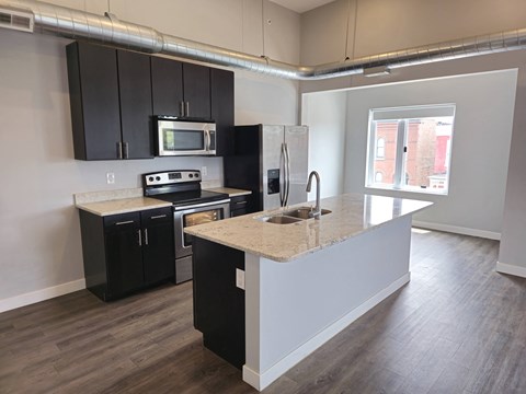 A kitchen with black cabinets and a granite countertop.