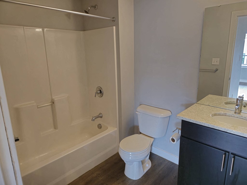 A white toilet sits next to a white bathtub in a bathroom.