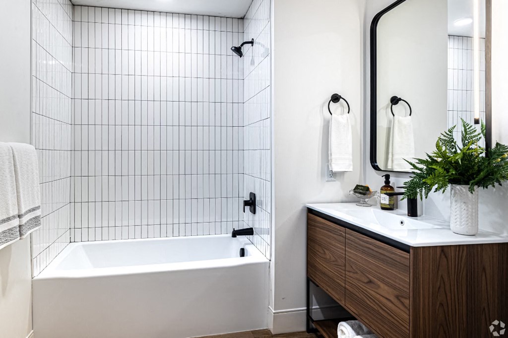 a white bathroom with a tub and a sink and a mirror