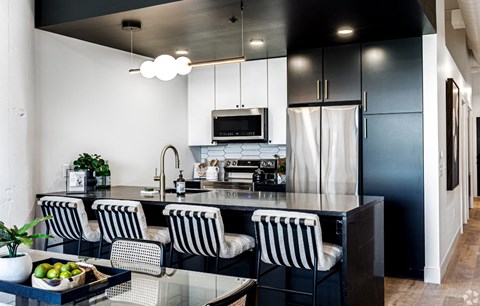 a modern kitchen with black and white cabinets and a counter with four chairs