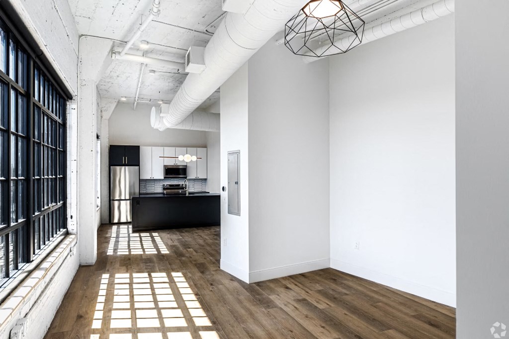 a living room with white walls and a window and a kitchen