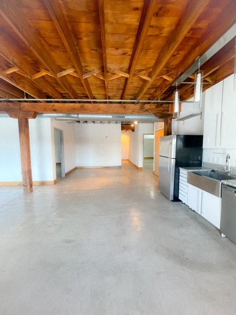 a kitchen and living room with white walls and a wooden ceiling