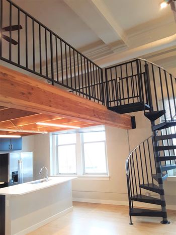 A spiral staircase with a black metal railing and wooden steps.
