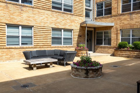 a patio with a couch and a table in front of a building a patio with a couch and a table in front of a building
