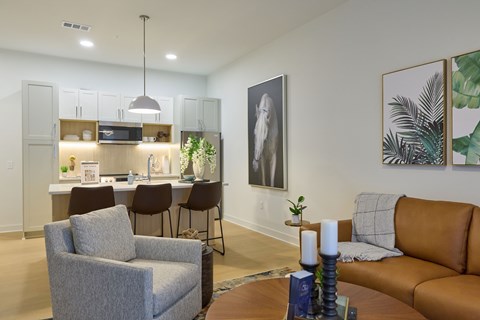 A living room with a grey armchair, a brown leather sofa, and a dining table with chairs.