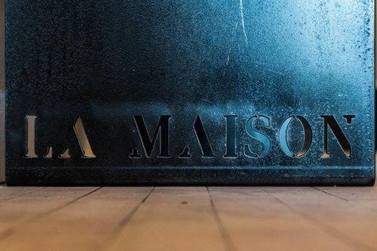 A blue sign with the word "LA MAISON" on it.