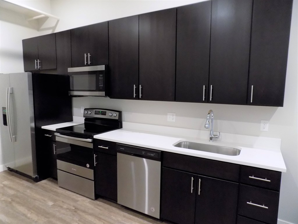 A kitchen with black cabinets and stainless steel appliances.